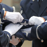 Military members fold an American flag at a funeral