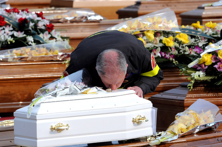 Grieving man kisses the coffin of a child