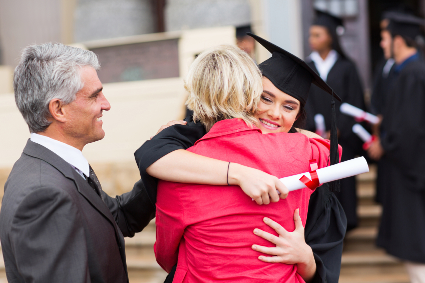 Happy young woman hugging parents at graduation despite student loan dent