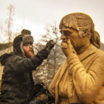 A Sand In Your Eye artist adds details to the sand sculpture's face, a grieving woman