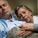 An exhausted caregiver sleeping next to her husband shows caregivers stress