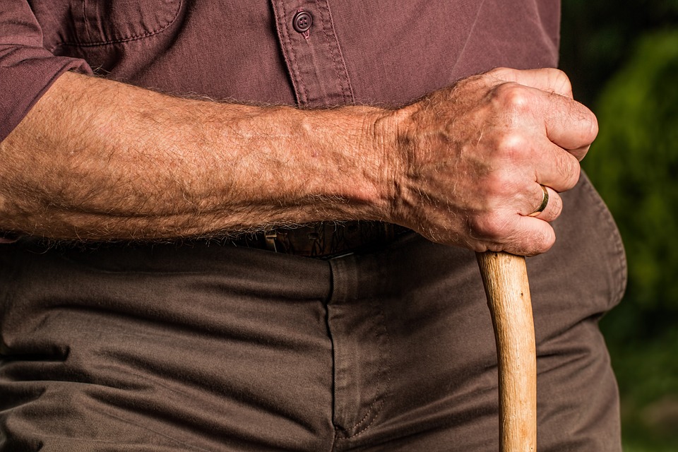 An elderly man holds a cane