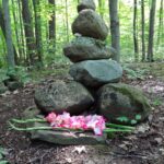 rocks placed in a forest with flowers for grief ritual
