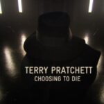 A screenshot from Terry Pratchett: Choosing to Die showing Pratchett in the shadows, wearing a black fedora hat