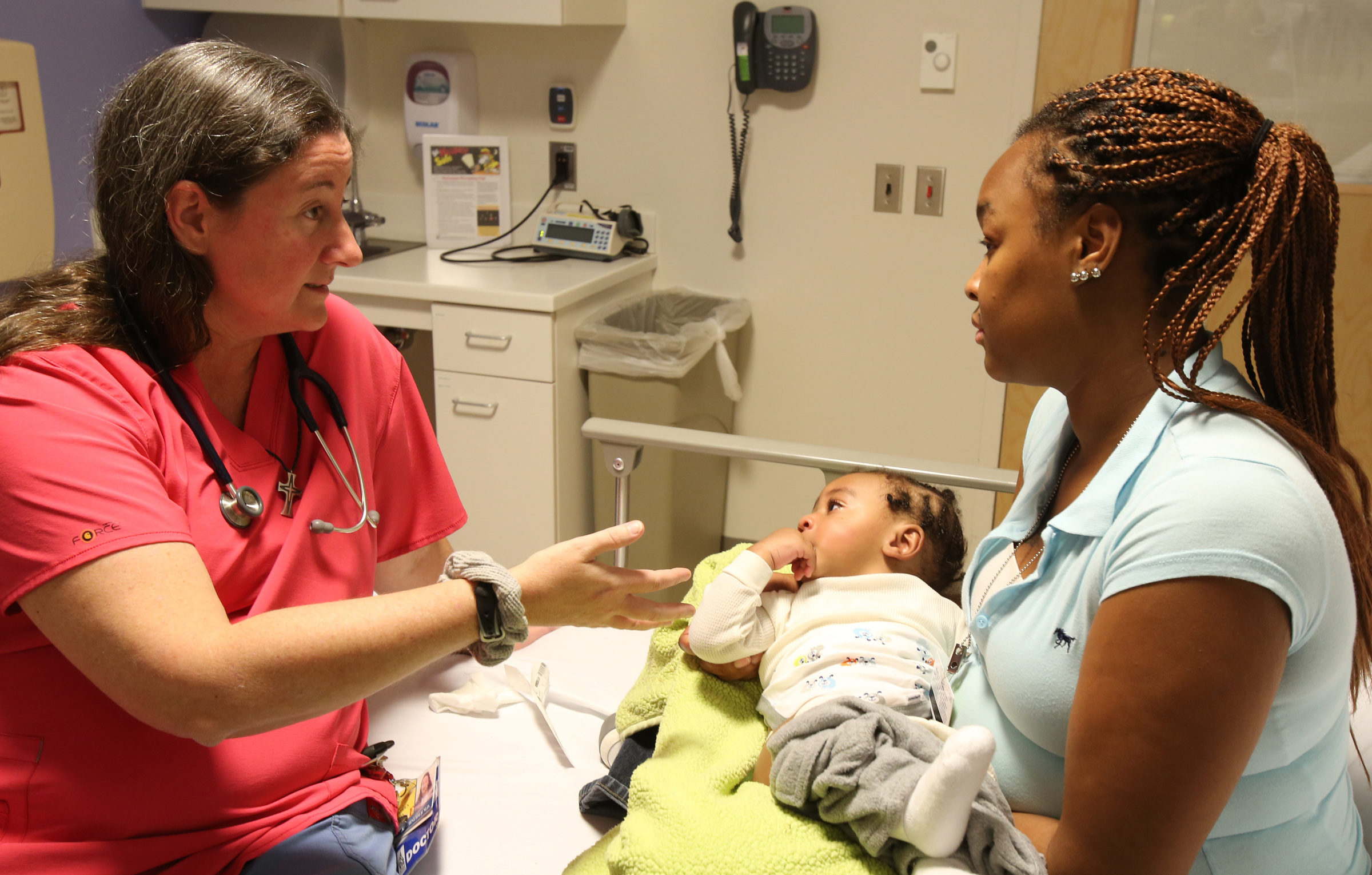 young African American women holds baby in doctor's office accessing healthcare