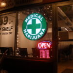 A medical marijuana building with a green sign and a medical cross at the center