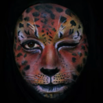 Emma Allen winking and wearing orange face paint that looks like a jaguar's face
