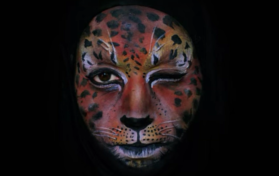 Emma Allen winking and wearing orange face paint that looks like a jaguar's face
