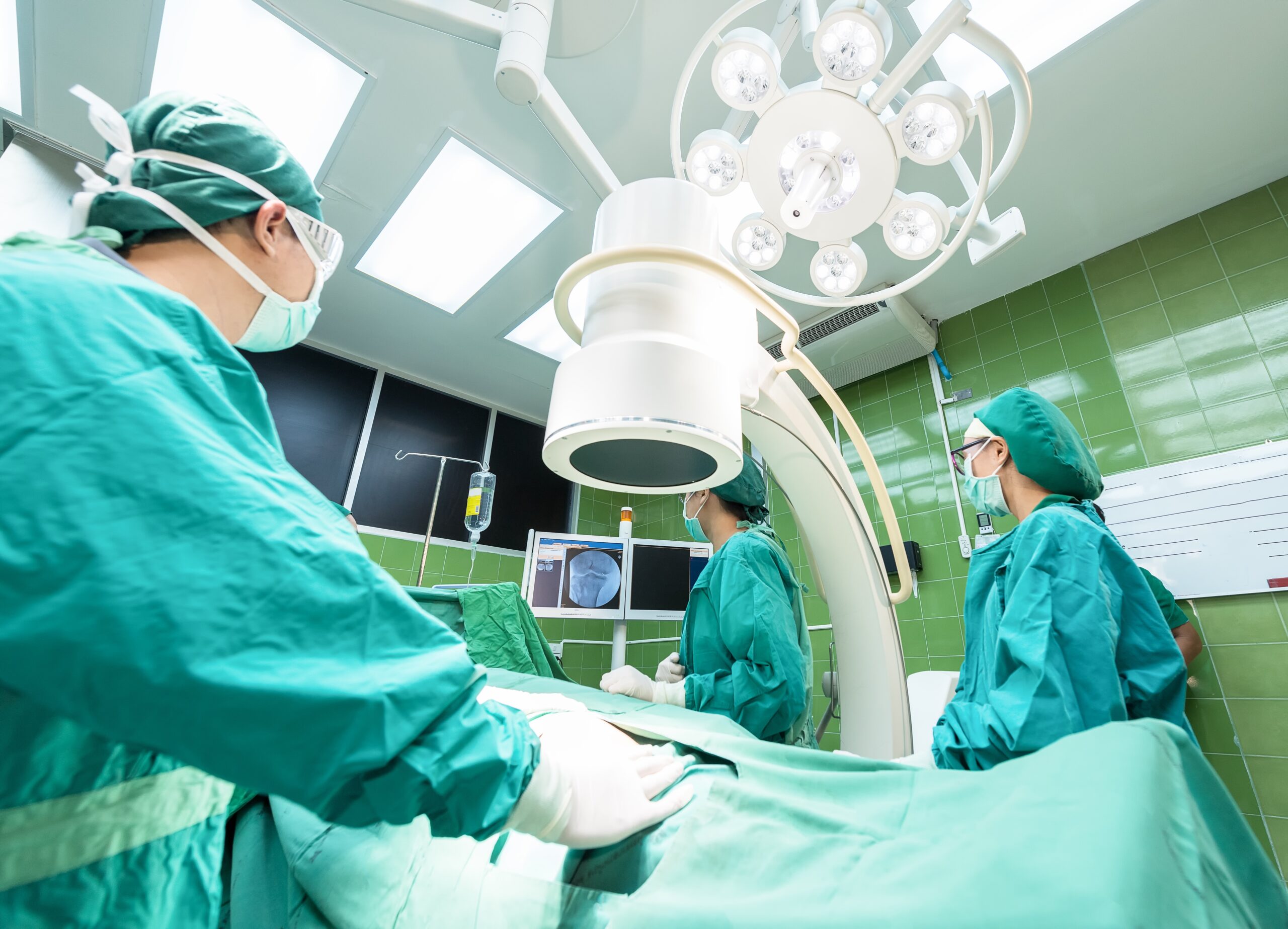Three doctors stand around a table to treat a patient