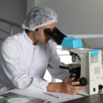 Scientists looks in microscope studying ALS drug