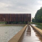 A photo of Hofheide Crematorium, featuring a long line of metal pieces lined up next to each other on the side of the building