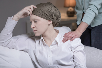 Female cancer patient in a head scarf looking stressed because of her illness.
