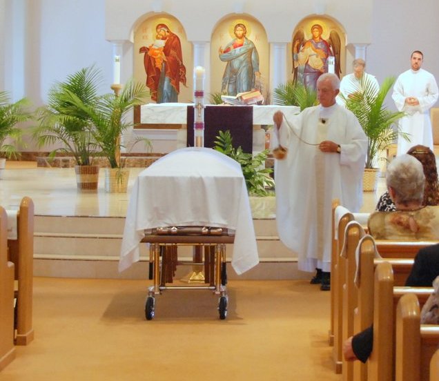Priest sprinkle holy water at a Catholic funeral Mass
