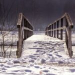 Wooden foot bridge covered in snow symbolizing the transition from life to death.