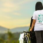 A hospice care nurse pushes a patient in a wheelchair outside
