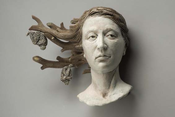 A sculpture about loss, featuring a woman's head, whose hair is being transformed into tree branches with two honeycombs hanging from the tips of the branches.