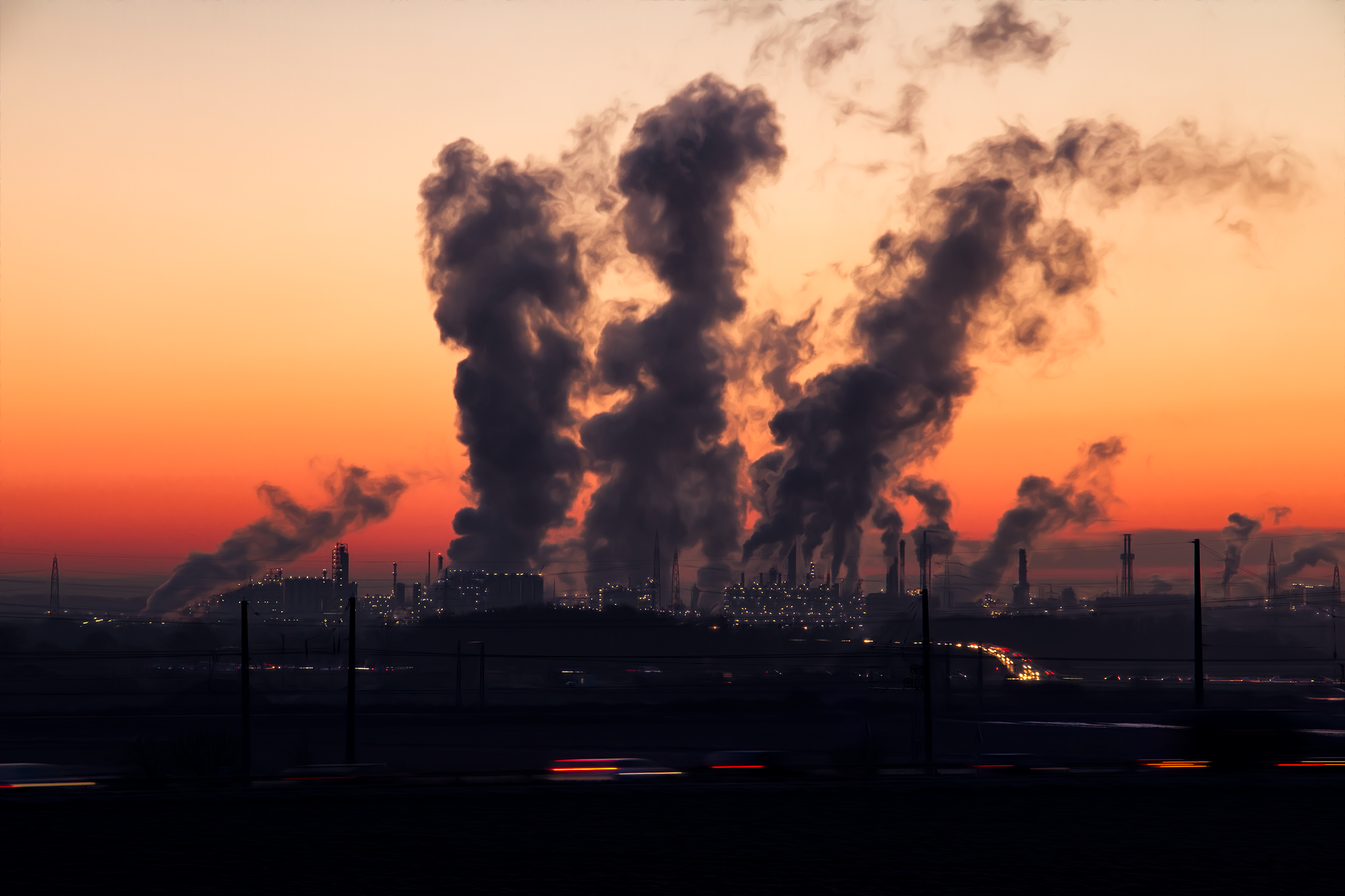 Factory smoke stacks emitting smoke at dusk.