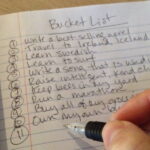 Photo of a hand writing a personalized bucket list.