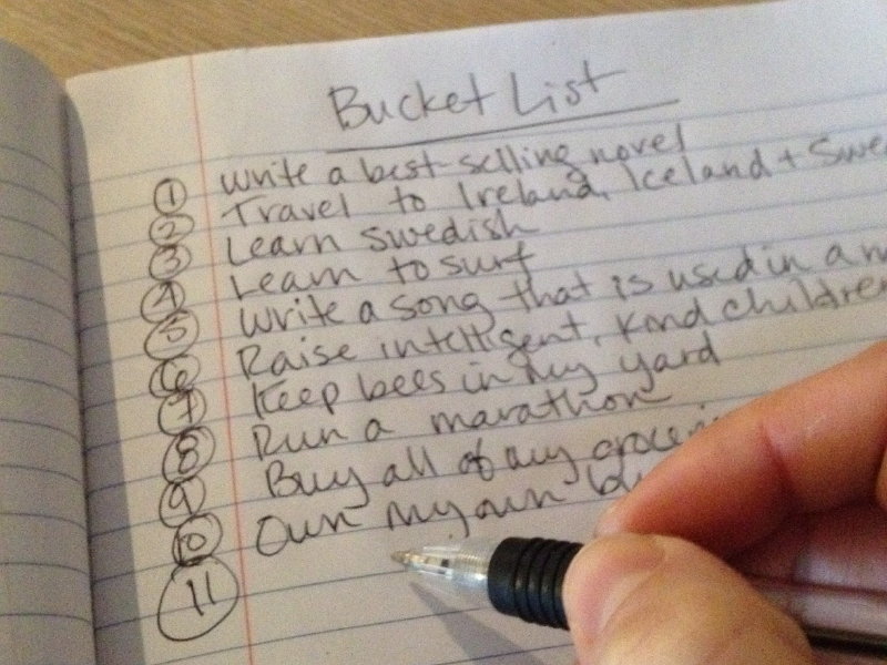 Photo of a hand writing a personalized bucket list.