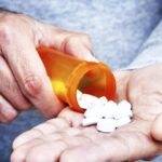 an old man's hands holding a bottle of pills gained by right to try laws