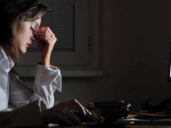 Woman clenching nose appearing tired while on computer.
