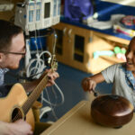 Child getting music therapy and playing a drum
