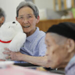 Image of a woman holding Paro, a caregiving robot