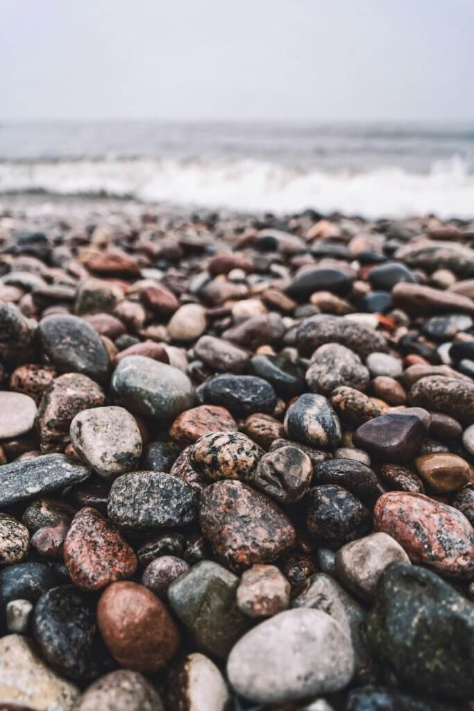 Close-up of smooth stones on a rocky beach with waves in the background