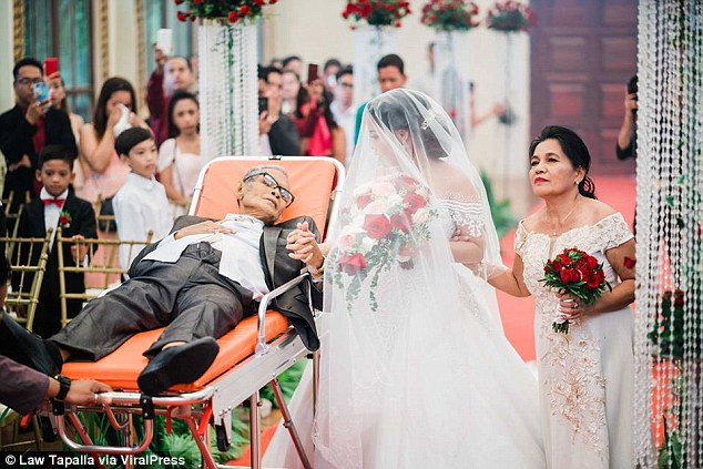 Photo of Pedro Villarin accompanying his daughter down her wedding aisle while laying in a stretcher.
