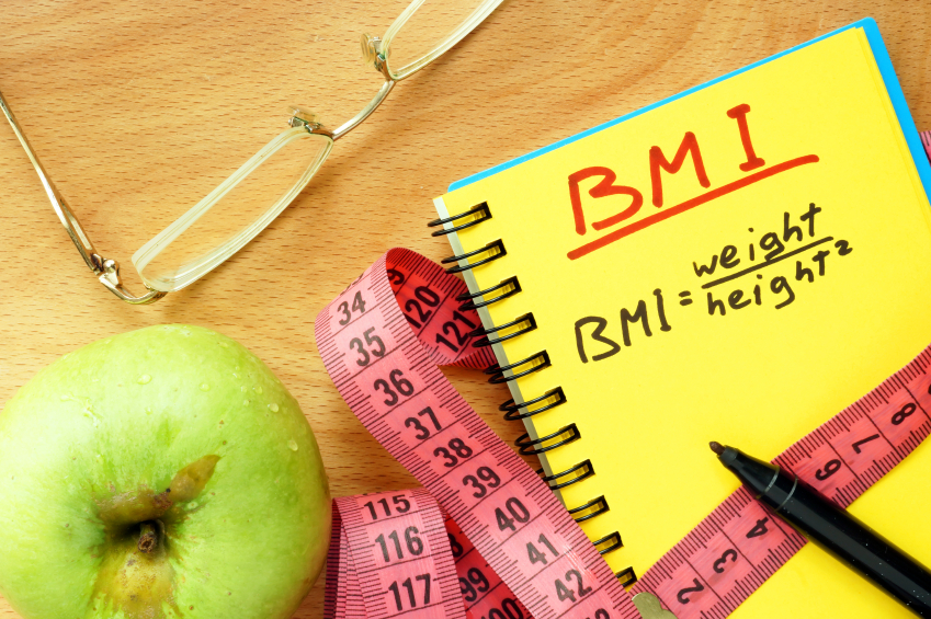 Apple, glasses, tape measure and a notebook that has the BMI equation.
