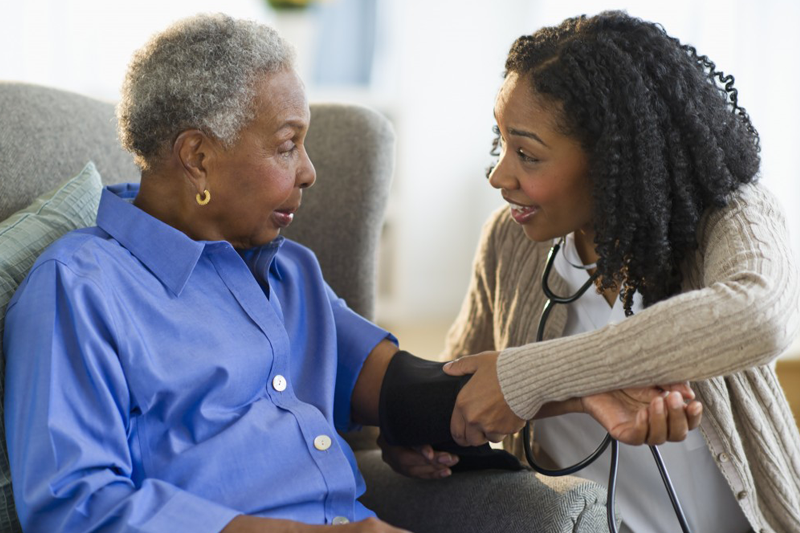 Young woman checking mother's blood pressure.