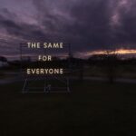 "The Same For Everyone" art installation illuminated against a dark sky.