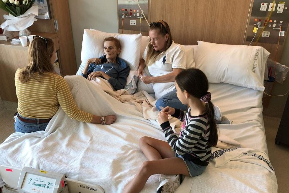 Dying woman lies in cuddle bed with her family