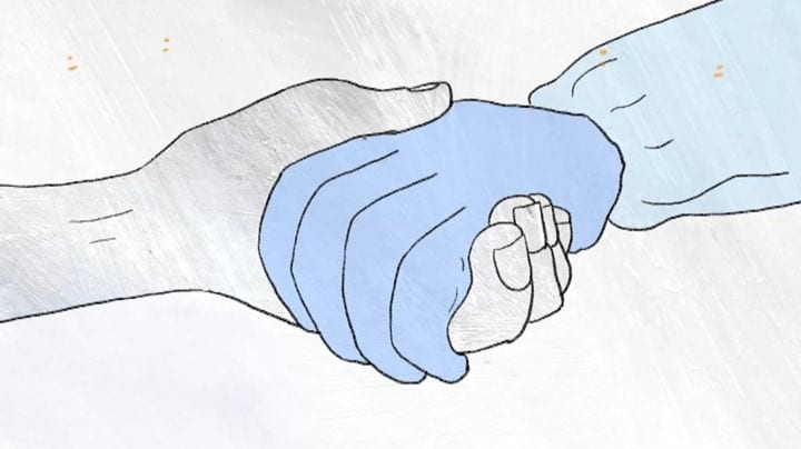 a gloved had holding a bare hand symbolizes end of life care during COVID-19