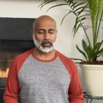 Les Aria, PhD, meditating in his home in front of a fireplace. Mr. Aria teaches patients to manage pain with mindfulness and meditation