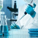 Scientific advancements have allowed scientists to reverse aging in cells; closeup of scientist wearing gloves injecting liquid into a test tube