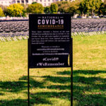 COVID-19 memorial sign in front of field full of folding chairs (national grief strategy)