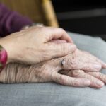 Hand on top of elderly hands in lap - vaccines for family caregivers