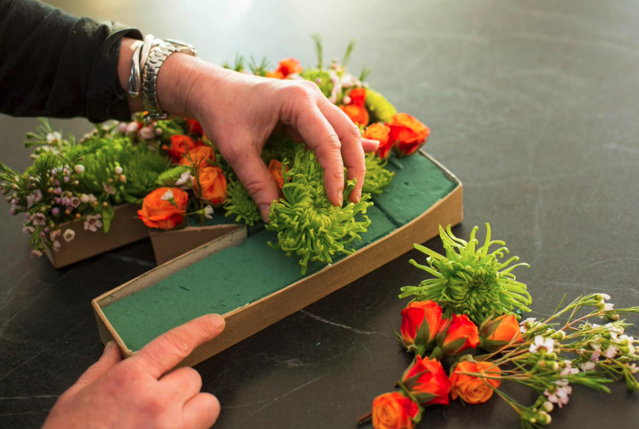 Person's hands assembling floral letter