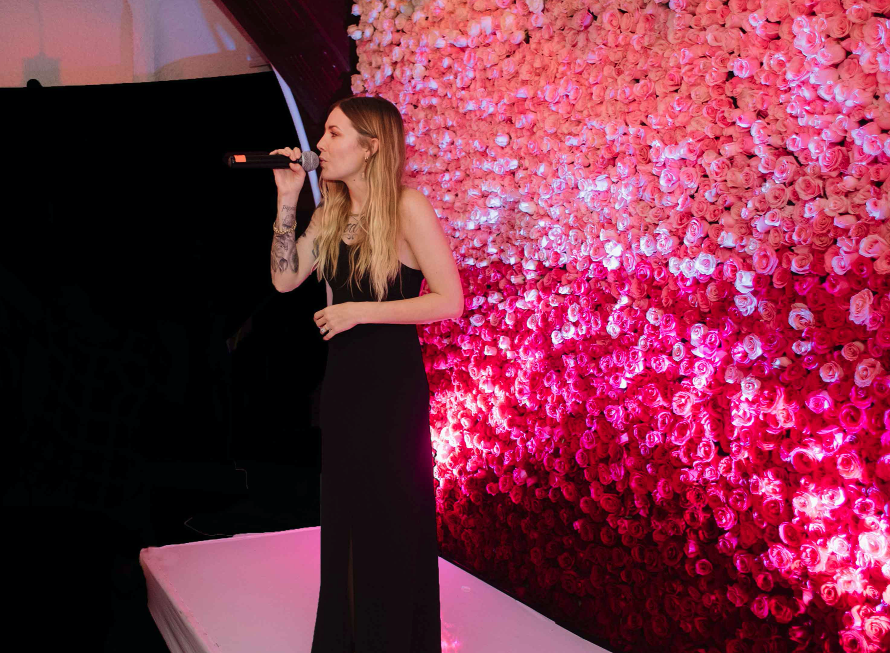 delivering a eulogy in front of wall of pink flowers