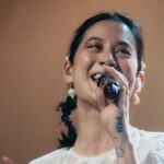 Michelle Zauner dressed in white, singing