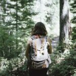 woman walking through forest with back