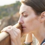 woman with depression looks over a railing