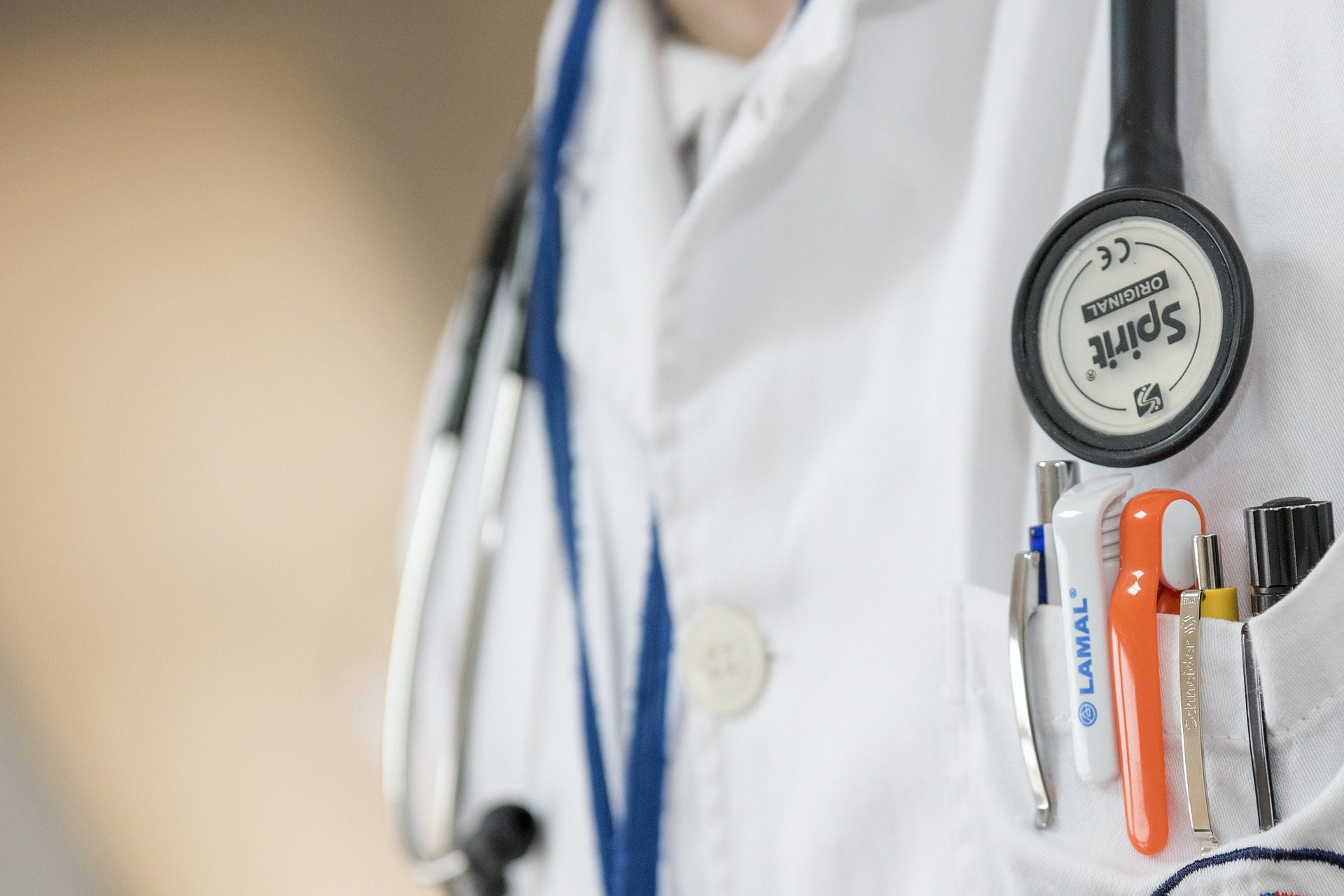person wearing a white lab coat with pens in pocket and stethoscope