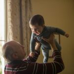 A grandfather joyfully tosses a baby into the air