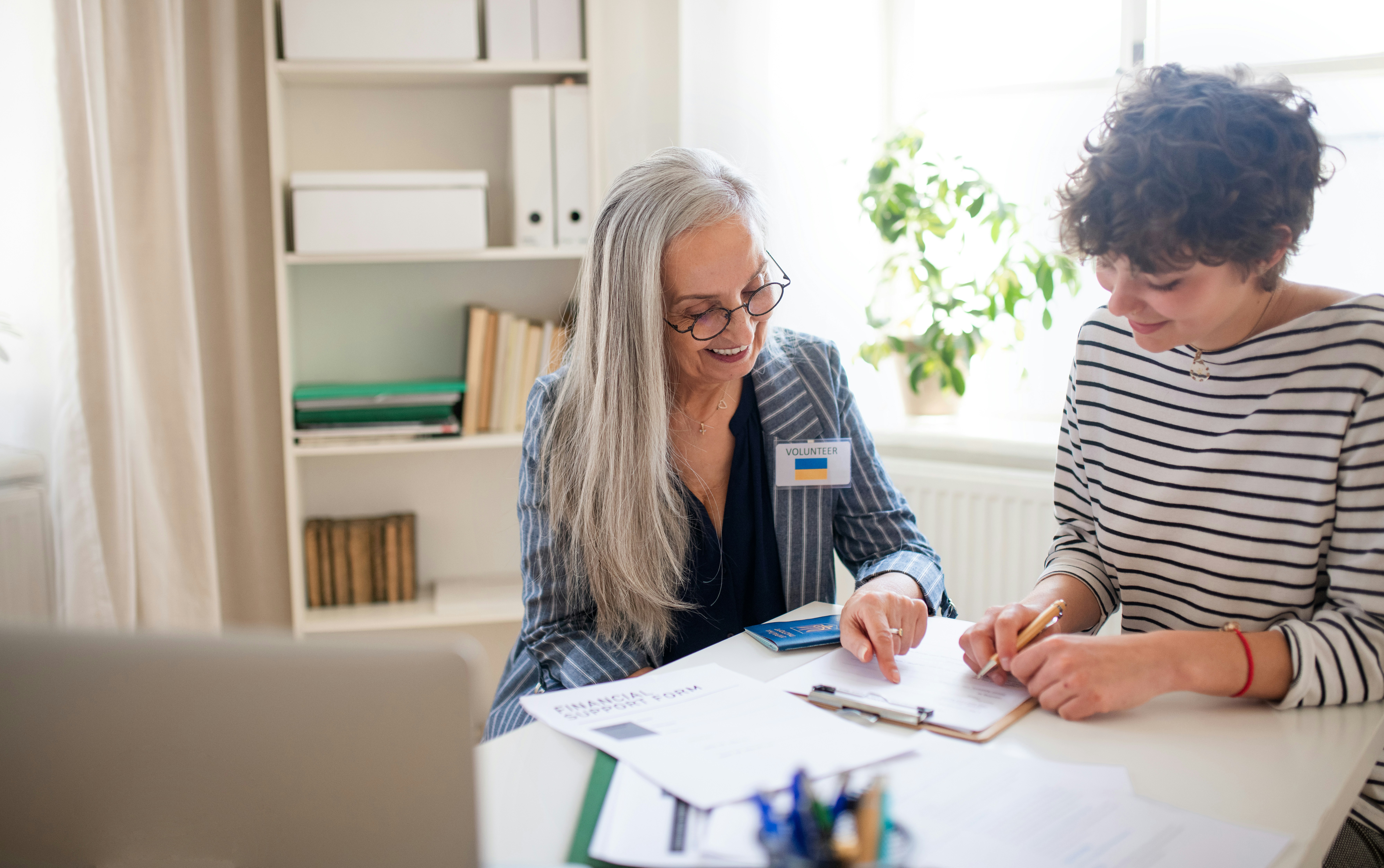 a younger woman is sitting at a desk with an older woman discussing the causes of dementia