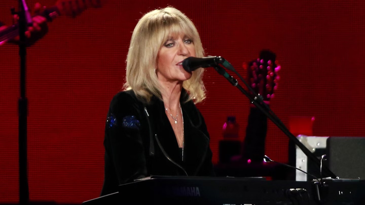 Christine McVie sings into a microphone at the piano