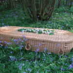 Environmentally friendly coffin sitting on grassy field.
