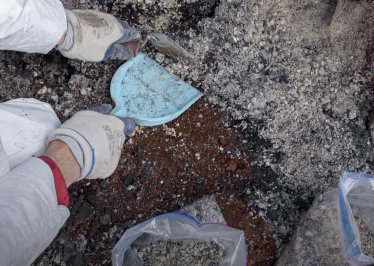 Close-up of hand using small plastic spade to collect cremains. 