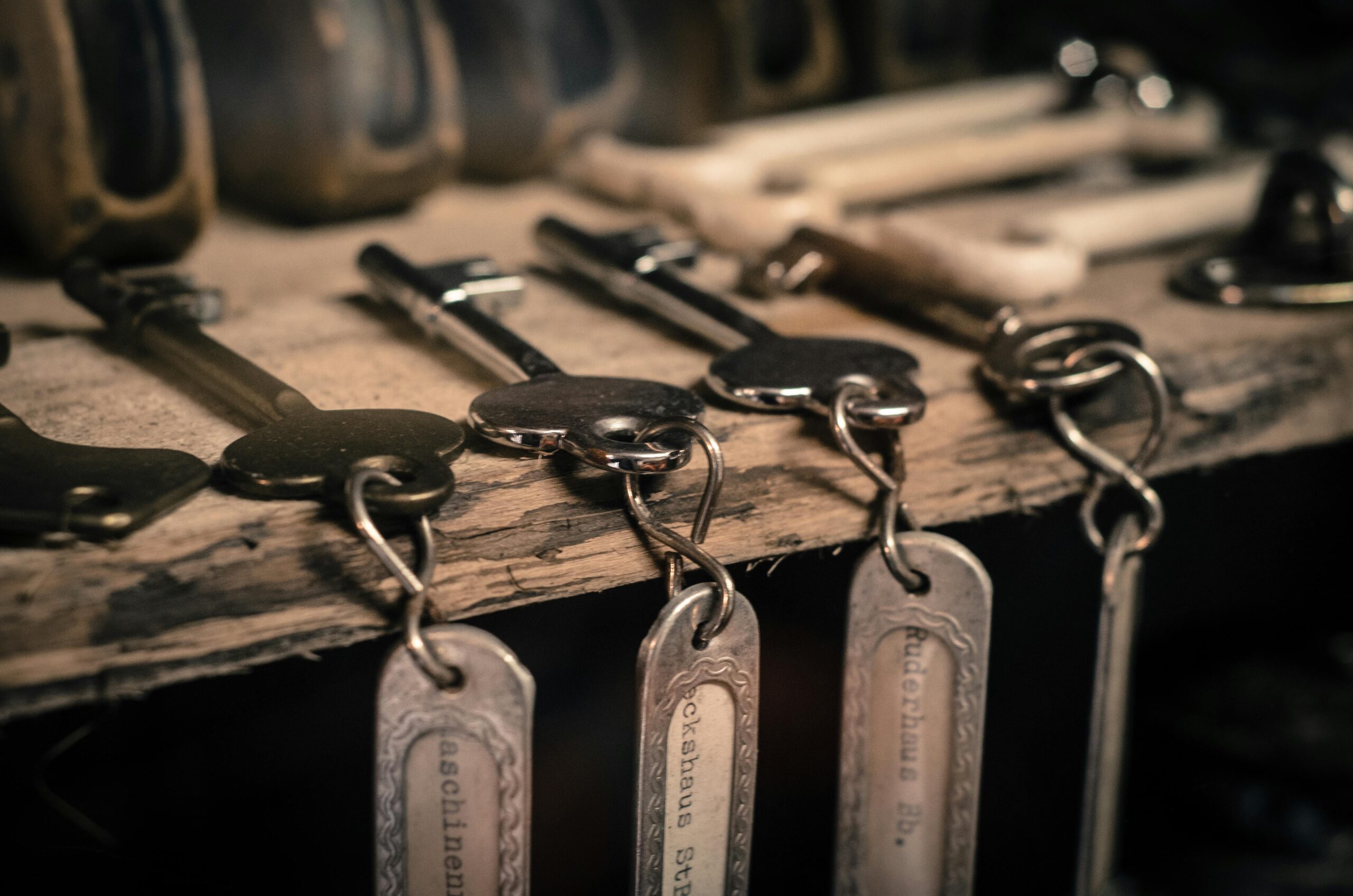 Keychains hanging from keys on a wooden shelf.
